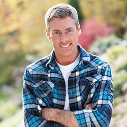 Man outside with arms crossed wearing plaid
